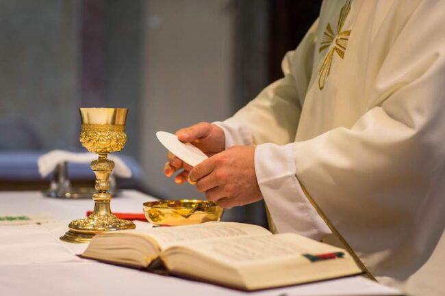 Priest during a wedding ceremony/nuptial mass (shallow DOF; color toned image)